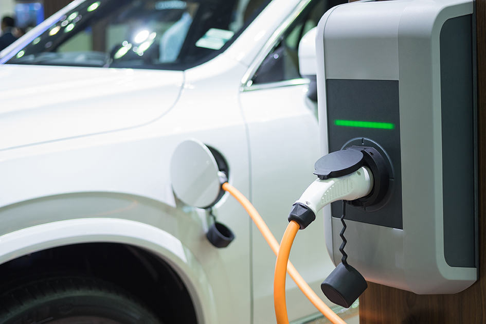 Charging an electric car with the power cable supply plugged in to a charger.