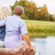 A couple in a common law marriage sit on a bench beside a pond