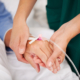 A medical nurse holds the hand of a patient who is allowed leave due to FMLA laws.