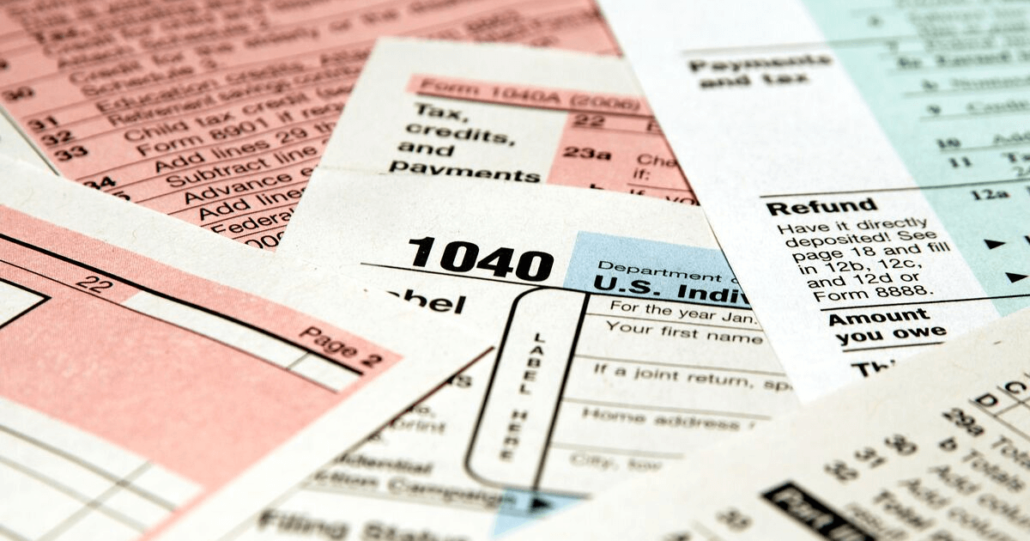 Various tax forms are shown, most prominently the form 1040 used to file annual tax returns.
