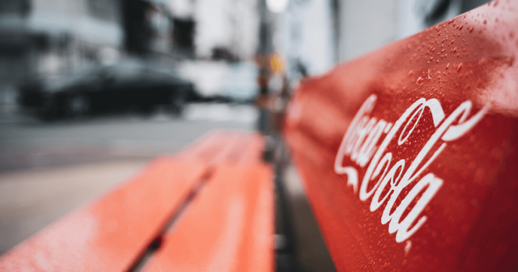 A bench with the Coca-Cola logo on it, ones of the most famous business names that is protected by trademark