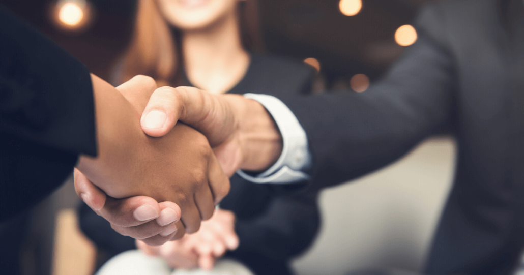 Two businessmen shake hands after they sign an acquisition deal