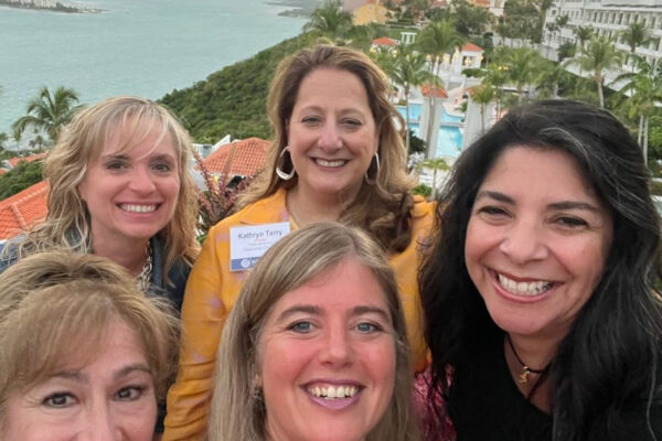 Five women pose for a photo at a rooftop terrace during a conference in Puerto Rico