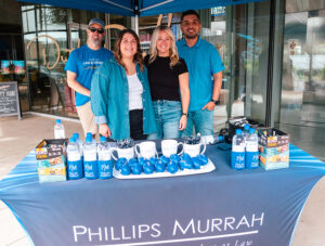 Phillips Murrah attorneys and marketers standing at the merch table at 2023 midtown walkabout event.