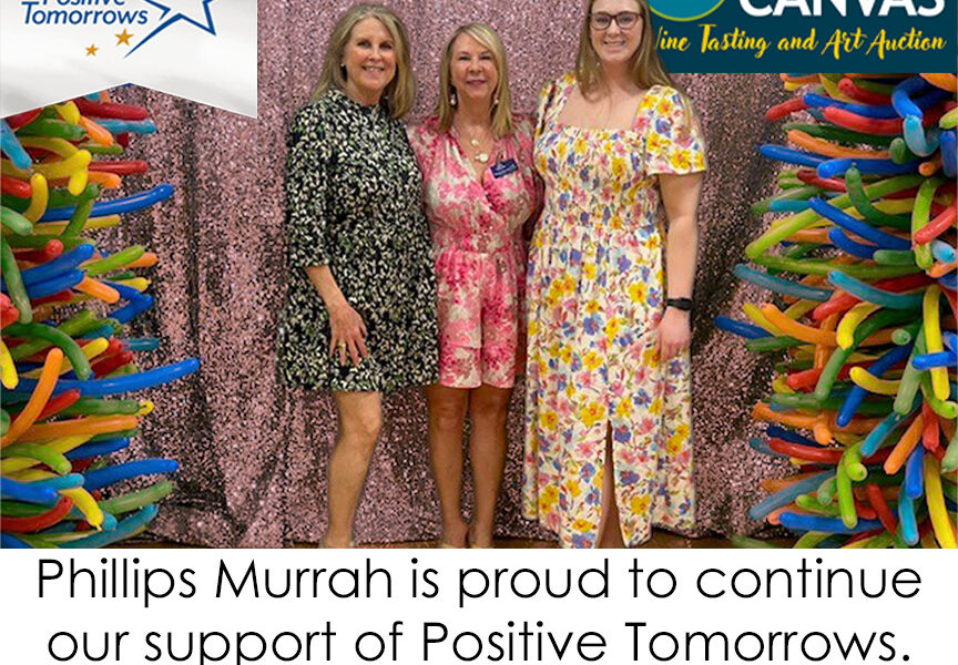 Three Phillips Murrah attorneys pose at the 2025 Cork & Canvas event, surrounded by colorful balloons, with logos for Positive Tomorrows and Phillips Murrah.