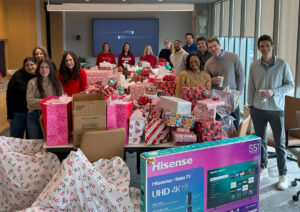 Phillips Murrah attorneys standing in a large conference room posing with presents they finished wrapping. 